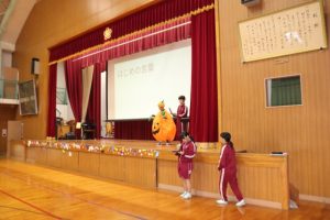 体育館でかぼちゃに扮装した児童がハロウィンクイズを出しています。
